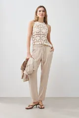 Pantalón de lino color beige con cintura elastizada con cordón ajustable, corte recto y pespuntes verticales al frente.