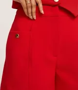 Short blanco de sastrería con cintura alta, bolsillos laterales con tachuelas metalizadas, recortes delanteros con costura aparente, bolsillos falsos y pinzas traseras.