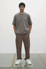 Pantalón cargo color marrón topo, de corte relajado, confeccionado en popelina de algodón. Cuenta con bolsillos al bies, bolsillos traseros con solapa y bolsillos laterales en las piernas con solapa y botones a presión.