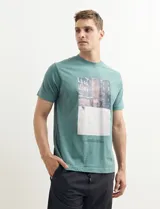 Remera color petróleo de manga corta con estampa de un edificio y texto en el frente.