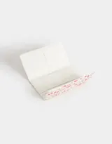 Billetera de cuerina con estampado de flores, fresas y cerezas. Tiene formato de fichero con solapa y broche en forma de corazón. Cuenta con compartimentos para tarjetas y billetes.