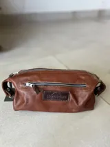 Necessaire de cuero color marrón con forro de lino, equipado con cierres en cobre.