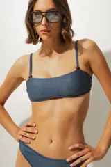 Top de bikini azul con textura, corte recto, tirantes finos y detalle de cuentas de madera en los tirantes.