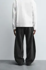 Pantalón de jean celeste con efecto lavado, corte holgado desde la cadera que se estrecha ligeramente en el bajo, tiro medio, cinco bolsillos y cierre frontal con cremallera y botón.