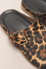 Sueco destalonado de cuero vacuno color negro, con hebilla ajustable, detalles de tachas doradas y suela de cuero.