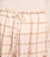 Conjunto de pijama corto compuesto por una remera de algodón blanca con estampado de mascotas y un short de viscosa a cuadros en tonos rosa y beige con volados en el ruedo.