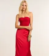 Vestido largo de satén color crema, con escote halter, espalda descubierta y abertura frontal. Presenta detalles de pedrería en el escote.