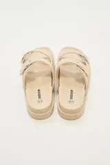 Sandalias bajas color beige con doble tira con hebilla y apliques de tachas.
