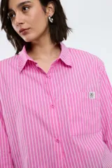 Camisa a rayas verticales rojas y blancas, de corte recto, con cuello clásico, manga larga y bolsillo en el pecho.