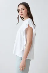 Blusa blanca de algodón con cuello redondo fruncido y mangas cortas con volados.