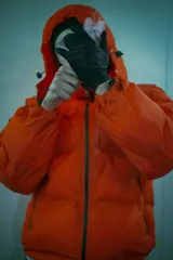 Conjunto puffer naranja con estampado del logo de la marca en negro. Incluye campera sin mangas con mangas desmontables, pantalón de jogging, gorro y tote bag. Resistente al agua y al frío.