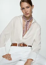 Camisa blanca de algodón con cuello camisero, manga larga con puños abotonados y cierre frontal con botones.