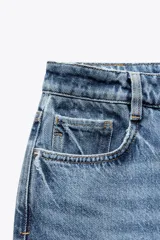 Pantalón de jean color crudo, de tiro alto, corte recto y largo tobillero. Tiene cinco bolsillos, cierre frontal con cremallera y botón metálico.