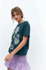 Remera lila de algodón con estampado de flores en tonos naranja y rosa.