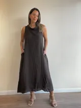 Vestido largo sin mangas color azul claro, confeccionado en lino, con cuello tipo buche o drapeado. Presenta un calce holgado y bolsillos laterales.