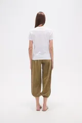 Remera blanca de algodón con cuello redondo y manga corta. Presenta un bordado lineal en tono claro, simulando formas orgánicas o florales, adornado con pequeñas mostacillas.