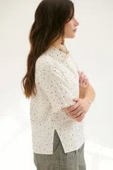 Camisa blanca con estampado de lunares negros, de corte clásico, manga corta y cuello camisero.
