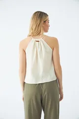 Blusa sin mangas color crudo, con cuello halter y cordón ajustable.