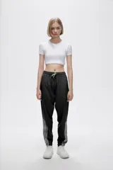 Pantalón de jogging color celeste con cintura elástica ajustable con cordón y puños elásticos. Presenta tres tiras verticales blancas en la parte inferior de la pierna.