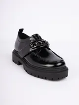 Mocasín de simili cuero negro con aplique metálico tipo cadena y cierre de velcro, con plataforma de 5 cm.