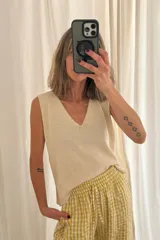 Chaleco de punto color crema, con escote en V y sisas amplias. Tejido artesanal en hilado 70% algodón y 30% acrílico.