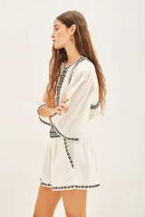 Minifalda blanca de algodón con bordados geométricos negros en el ruedo y cintura.