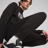 Pantalón de jogging chupín negro con logo Puma estampado en blanco en la pierna izquierda.