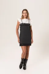 Vestido corto negro con lunares blancos, breteles finos regulables, escote recto con puntilla y terminación con puntilla. Cierre lateral invisible.