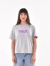 Remera gris con estampado frontal con la palabra 'TRUE.' en color violeta.