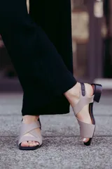 Sandalias de cuero color beige con tiras cruzadas y hebilla lateral. Taco cuadrado color marrón oscuro.