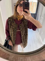 Chaleco reversible con un lado de corderito negro y otro de tussor con estampado animal print.