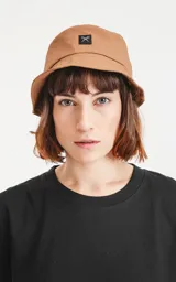 Gorro tipo bucket color marrón con logo de la marca en etiqueta negra.