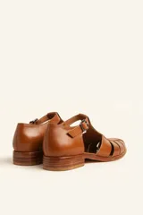 Sandalias de cuero color marrón claro, con diseño de tiras entrecruzadas y hebilla lateral.