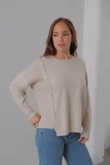 Sweater beige de punto, corte recto, cuello redondo y detalle de botones en el lateral.