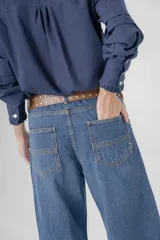 Pantalón de jean azul, corte recto y extra largo, con aplique de denim y ojalillo en una pierna.