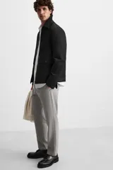 Pantalón slim fit negro confeccionado en tejido con elasticidad en ambas direcciones. Cuenta con bolsillos frontales y traseros de vivo con botón. Cierre frontal con cremallera y botón.