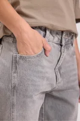 Pantalón de jean gris de corte ancho con bolsillos laterales y pañuelo estampado atado a la cintura.