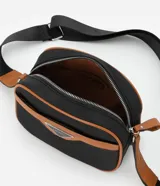 Cartera bandolera negra con detalles en marrón, confeccionada en poliéster certificado Grs y poliuretano. Presenta un aplique metálico triangular, asa larga ajustable y cierre por cremallera.