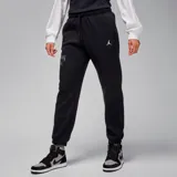 Pantalón de jogging negro de corte holgado, con cintura elástica ajustable con cordón, bolsillos laterales y puños elásticos. Logo de Jordan en blanco en la pierna derecha y estampado con la inscripción "DAN 4" en la pierna izquierda.