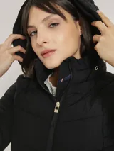 Campera acolchada negra con cierre de cremallera, cuello alto con capucha, mangas largas y bolsillos laterales con cremallera.
