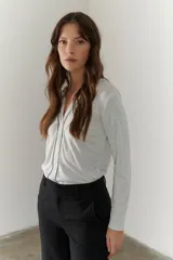 Remera blanca de mangas largas con escote en V y costuras decorativas en negro.