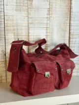 Bolso bandolera color borgoña con textura símil piel de cocodrilo, con correa fina ajustable y dos bolsillos frontales con cierre de broche metálico.