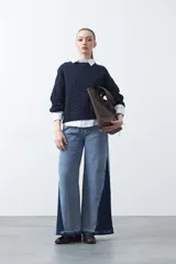 Jean de fit ultra wide confeccionado en denim de algodón, con una silueta bien amplia desde la cadera que aporta caída fluida y movimiento. El diseño destaca por su panel lateral en contraste, que estiliza visualmente la pierna y suma un guiño moderno al clásico jean.