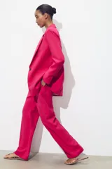 Pantalón de tiro alto color fucsia, con bolsillos delanteros y falsos bolsillos de vivo en la espalda. Tejido con efecto arrugado, pernera recta y cierre frontal con cremallera, botón interior y gancho.
