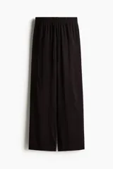 Pantalón culotte negro de viscosa con cintura elástica y cordón ajustable. Tiene bolsillos laterales y corte amplio.