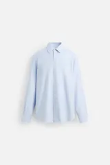 Camisa celeste de algodón, corte regular fit, con cuello italiano, manga larga con puños abotonados y cierre frontal con botones.