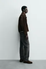 Cazadora de hombre de corte relajado confeccionada en piel con acabado ante, color marrón oscuro. Presenta cuello solapa, manga larga con puños abotonados a presión, bolsillos de vivo en cadera, bolsillo interior y bajo con elástico. Cierre frontal oculto por solapa con botones a presión.