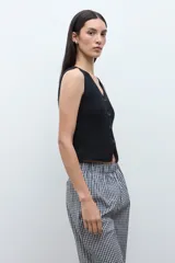 Chaleco de punto color beige melange, con escote en V y cierre frontal de dos botones oscuros. Es sin mangas y de corte ajustado.