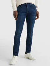 Jeans de denim azul oscuro con efecto desteñido en la parte delantera, corte ajustado, cierre de cremallera con botón y diseño de cinco bolsillos.
