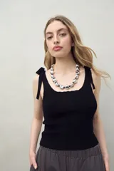 Top tejido de punto negro con tirantes finos que se anudan en los hombros.